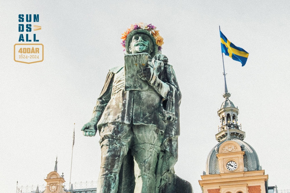 Statyn av Gustav den andre Adolf på Stora torget i Sundsvall. I bakgrunden finns en svensk flagga. 
