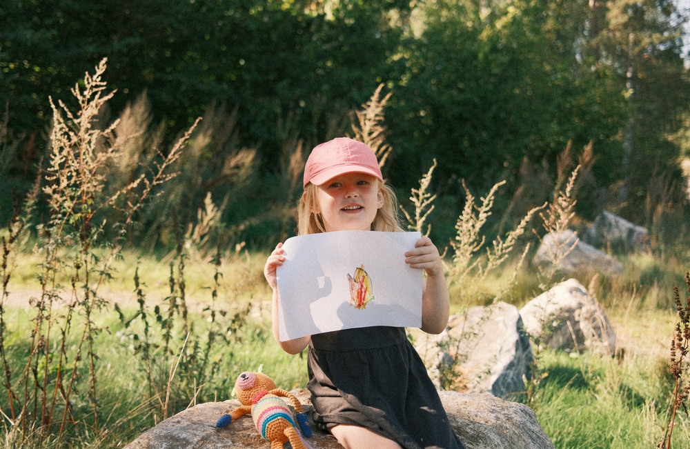 Frida, 4 år, håller en teckning med ett hjärta i olika färger.