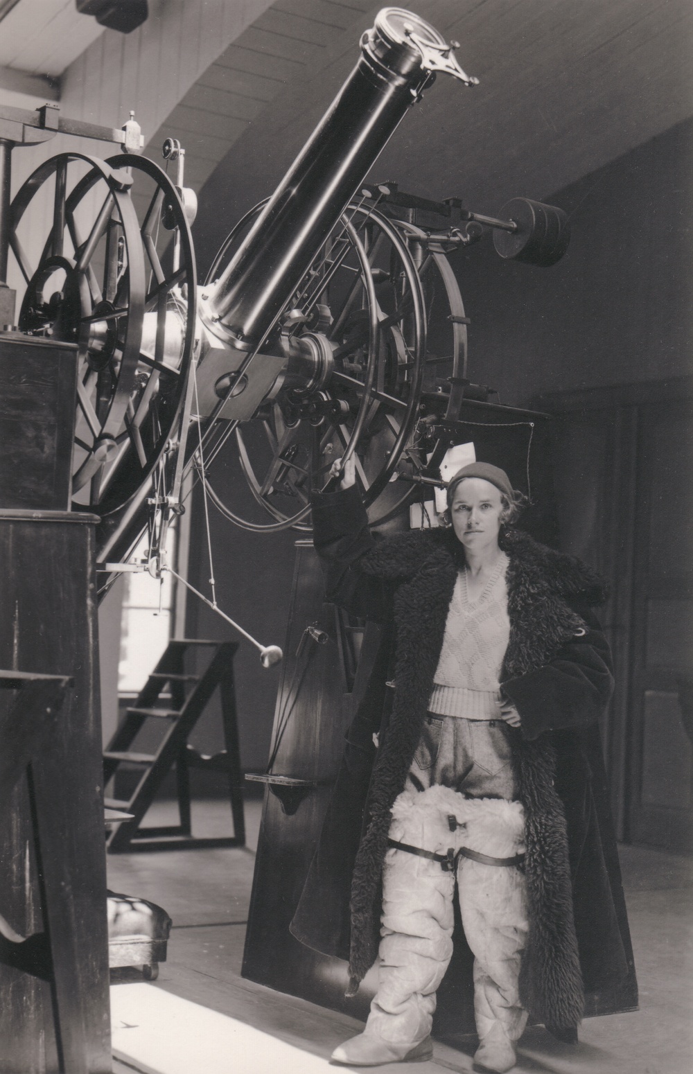 Frida Palmér var Sveriges första kvinnliga filosofie doktor i astronomi, verksam i Lund, som av ekonomiska skäl tvingades avsluta sin lovande forskarkarriär. På bilden står hon vid meridiancirkeln på Lunds observatorium omkring 1929. Den tjocka rocken och stövlarna är hennes speciella arbetsklädsel som behövdes för skydd mot nattkylan i observatoriet. Foto: okänd fotograf, Fysiska institutionen vid Lunds universitet. 