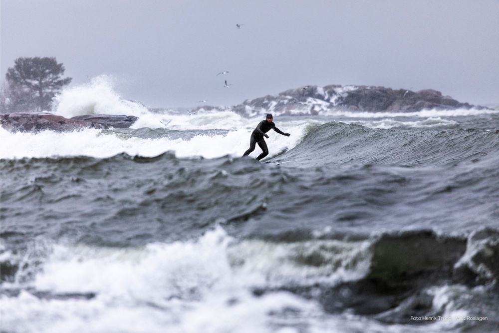 Surfare i vintrigt och stormigt vatten med höga vågor.