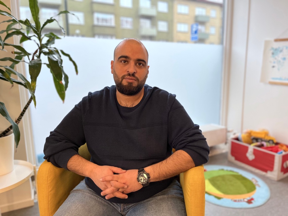 Amro Amer sitter i en gul fåtölj på Malmö mot Diskriminerings kontor