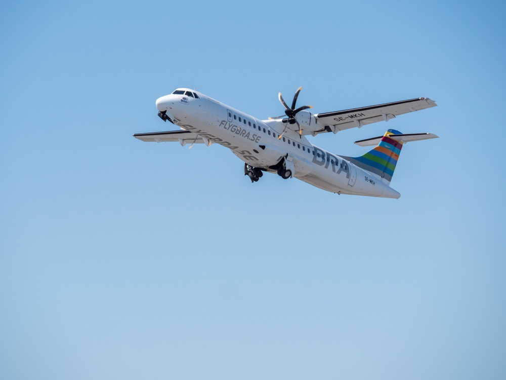 Ett av flygbolaget BRAs flygplan av modellen ATR 72-600 i luften med blå himmel 