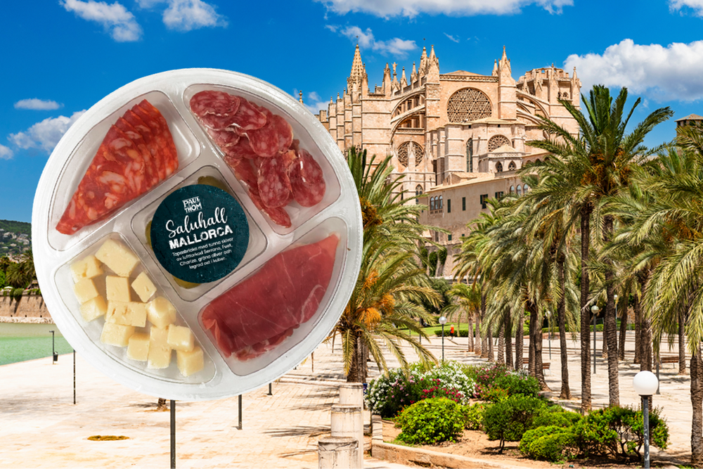 Tapasbricka med lufttorkad chark, ost och oliver. I bakgrunden syns katedralen i Palma.