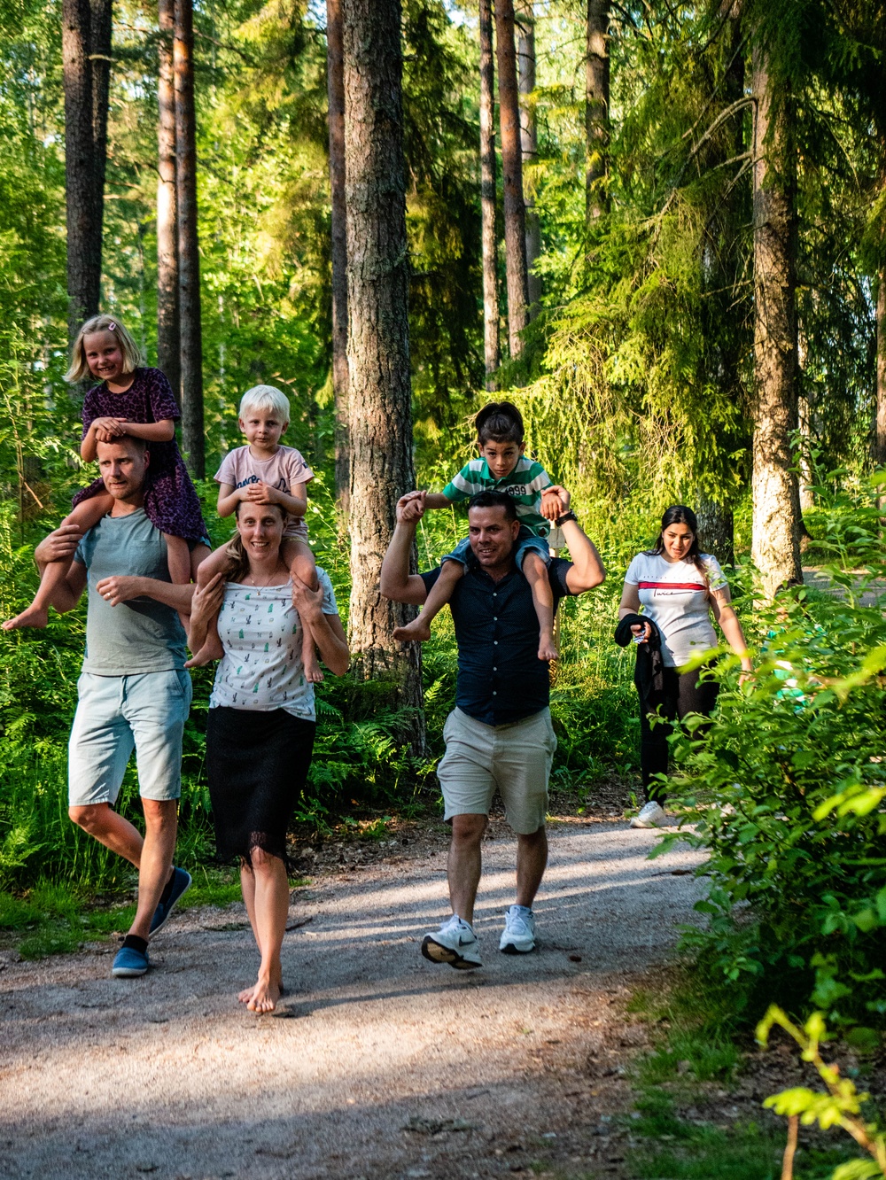 Vuxna som bär barn på sina axlar i skogen.