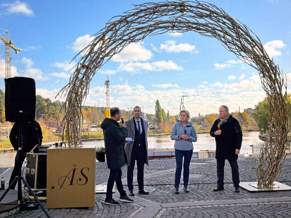 Människor står under prydnadsbåge i stadskärna