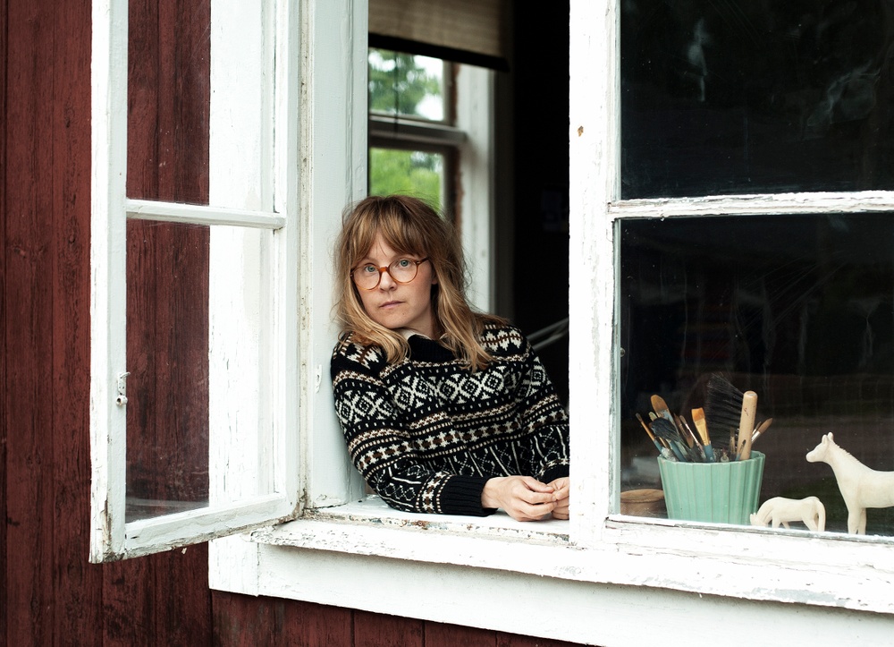 Porträttfoto på Emma AdBåge i öppet fönster. 