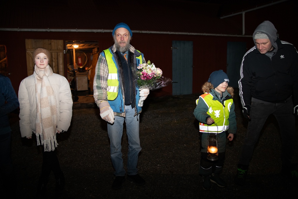 Scoutledaren Mats Olsson med en bukett blommor, omgiven av scouter vid Lionsgården.