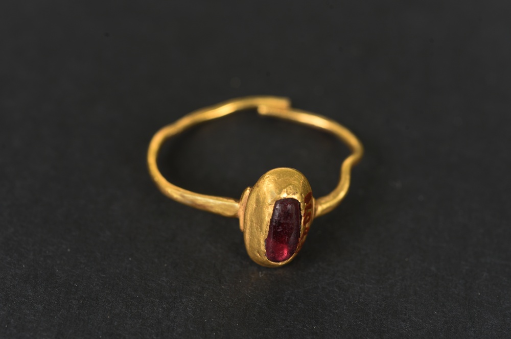 En fingerring av guld med en infattad sten, som anses vara en almandin (en granat). Ringen grävdes fram vid korsningen Stora Södergatan och Kattesund i Lund. 
