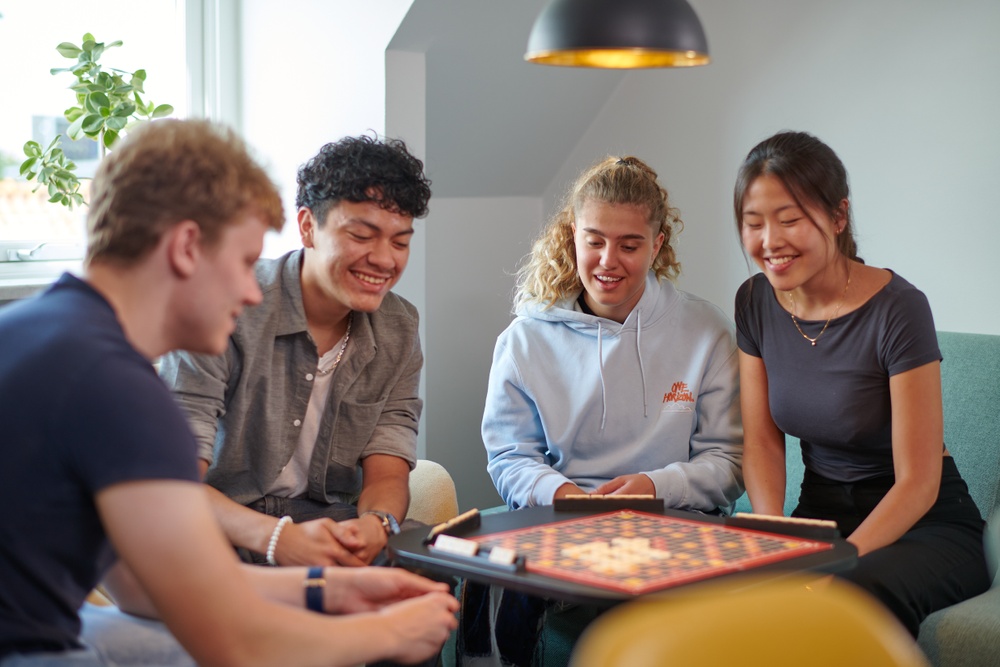 Fyra studenter sitter och spelar sällskapsspel i korridorkök på Tomegapsgården. 