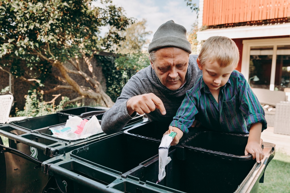 Man och barn sorterar sopor i fyrfackskärl