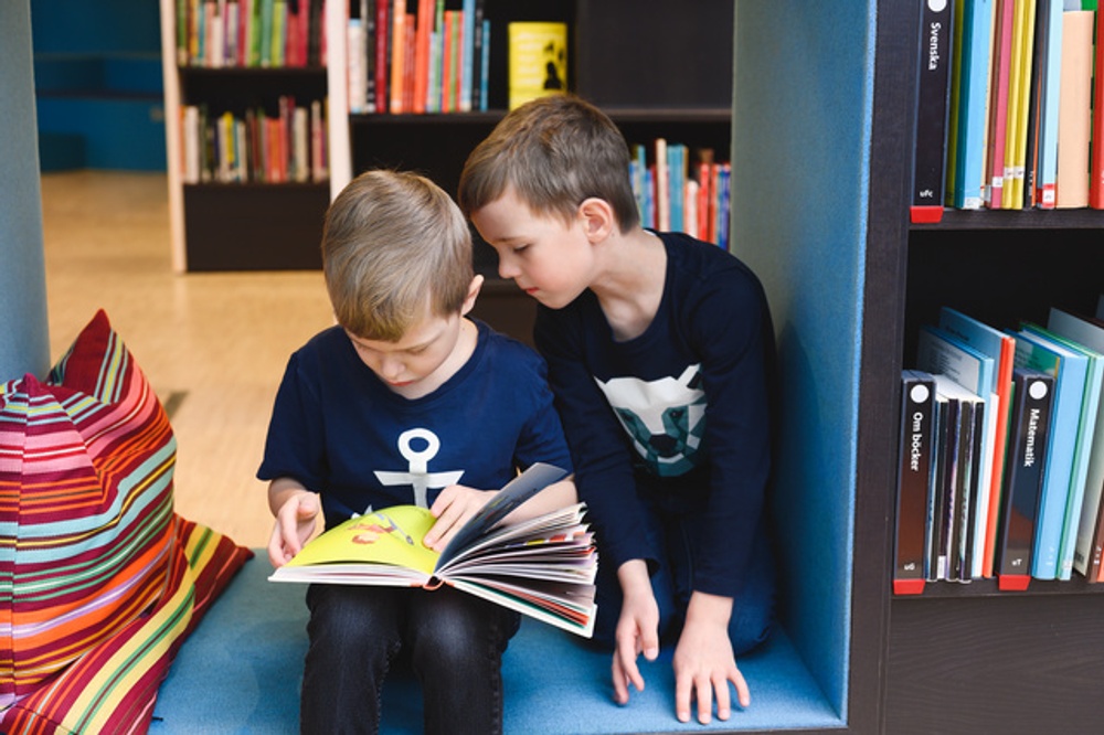 Barn läser en bok på ett bibliotek