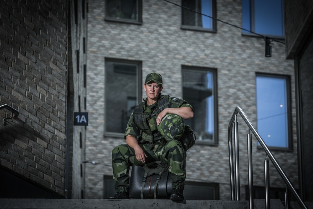 Kvinna i militär uniform sitter på sin utrustning i en trappa.