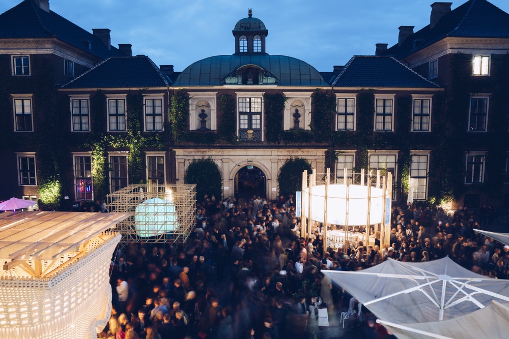 Several architectural pavilions are seen in the courtyard of an historic bulidings.