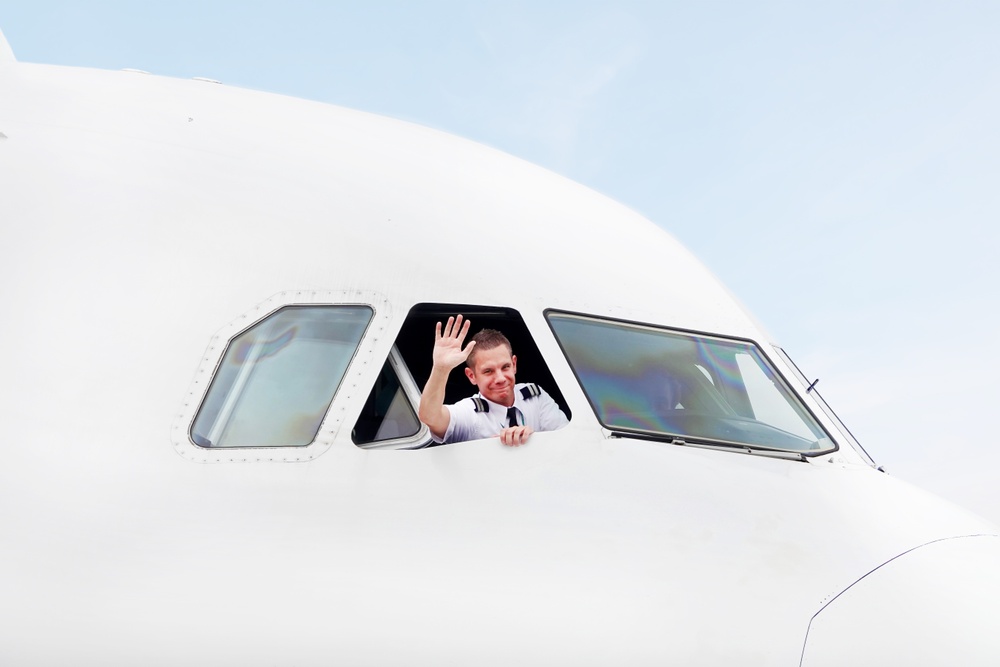 En av piloterna från flygbolaget BRA vinkar från ett öppet fönster i cockpit i flyplanstypen Airbus A319