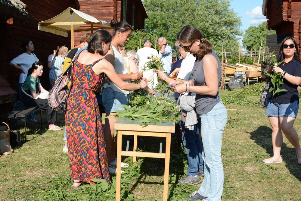 Besökare hjälper till att smycka midsommarstången