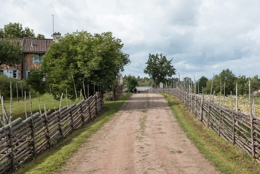 Kulturreservatet Smedstorps dubbelgård. Exteriörbild med grusväg och gärdesgård.