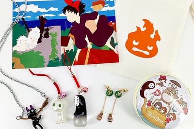 Items from a Fangirl Monthly subscription box, including pendant necklaces with characters from Studio Ghibli and a button.