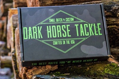 A closed Dark Horse Tackle subscription box on a wood pile.