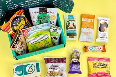 An open SnackSack subscription box filled with cranberry and almonds, cashew cookies, peanut butter cookies and more.