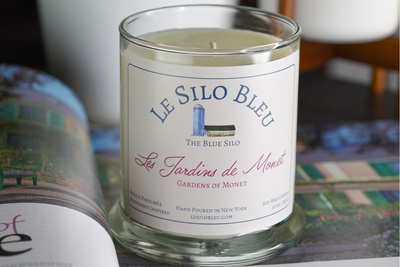 large les jardins of monet candle sitting on a french magazine showing Monet's house and garden in Giverny, France- green shutters visible.