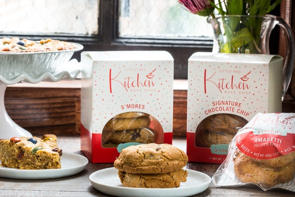 Cookies on a plate in front of subscription boxes of cookies labeled Little Red Kitchen.