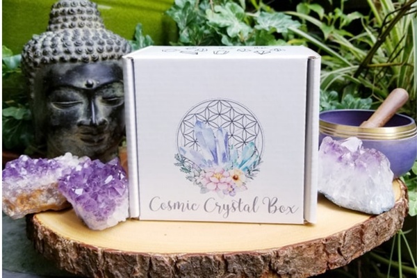 A Cosmic Crystal Box sits on a tree stump with amethyst crystals all around it.
