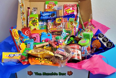 An open The Munchie Box subscription box filled with Reese's Pieces, Oreo's, Dots, Pop Rocks, and Sour Patch Kids.