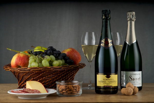 Items from Club Cuvée - Champagne Club subscription box including 2 bottles of champagne, a basket of fruit, and almonds.