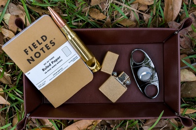 Items from an America's Crate subscription box including a lighter, a cigar cutter and  a field notebook and pen.