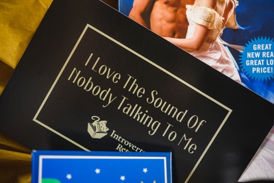 Insert card that says I Love The Sound Of Nobody Talking To Me. On top of a book with a yellow background.