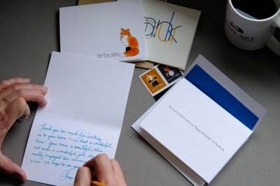 A person writing a note inside a card from a Lost Art Stationary subscription box.