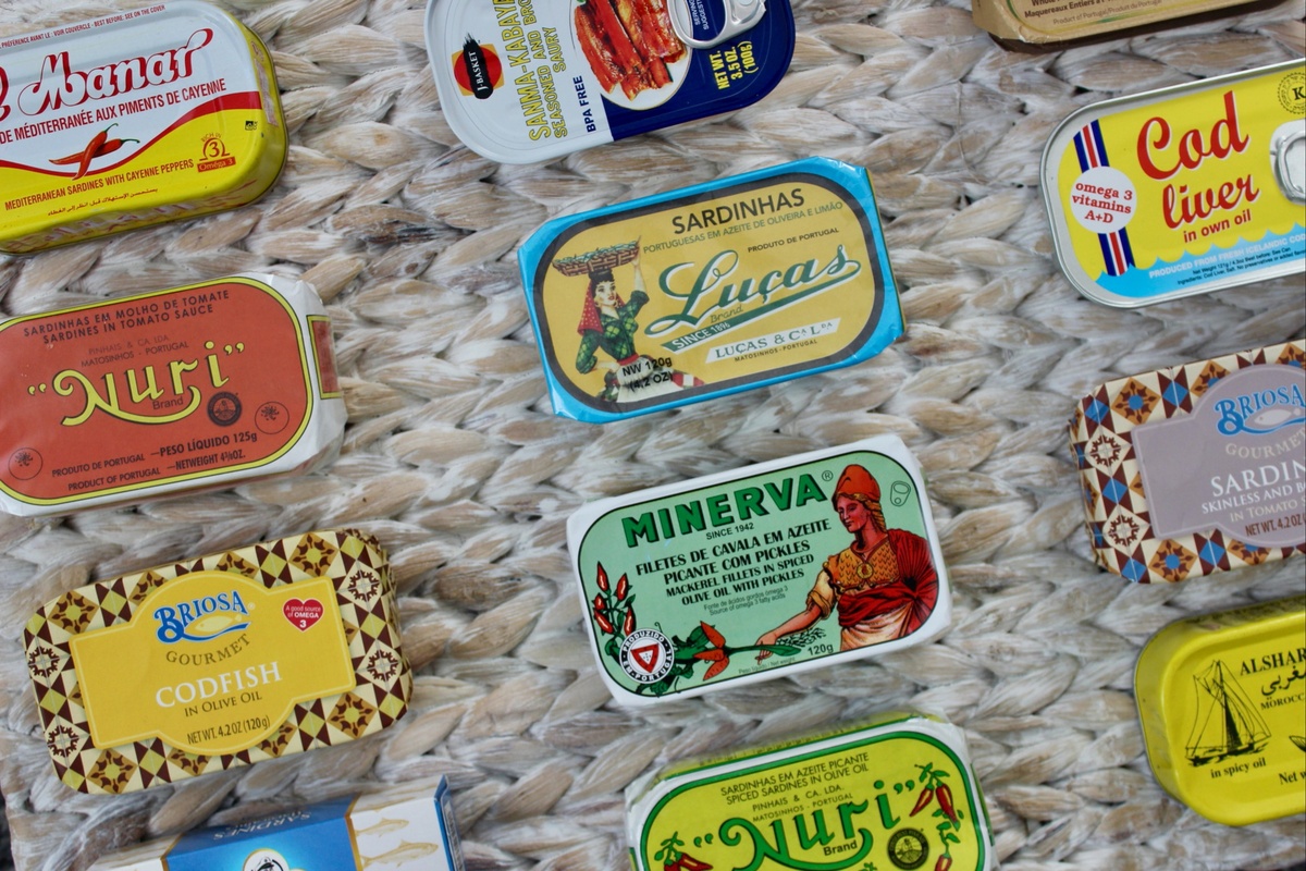 Items from a Tinned Fish Club subscription box, including 12 tins of tinned fish.