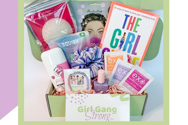 A Girl Gang Strong subscription box filled with a book, nail polish, face masks, a scrunchie, deodorant and a face sponge.