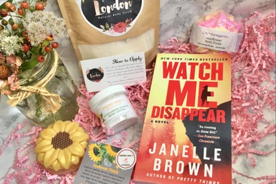 Items from a Bubbles and Books subscription box, including a book, a sunflower bath fizzle, body scrub and body lotion.