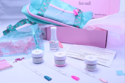 An open Sparkle & Co. Luxe Nails subscription box, with nail polish, nail color samples, and a tote bag.