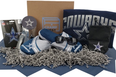 A closed Champ-Chest subscription box surrounded by Cowboys football memorabilia including slippers, a hat, and a jersey.
