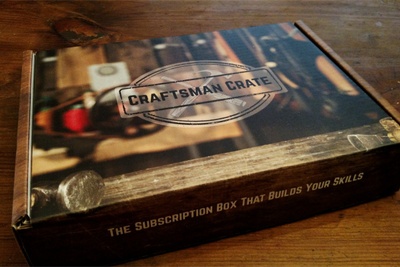 A subscription box labeled Craftsman Crate sitting on a wooden table.