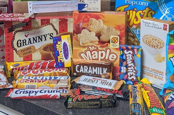 Items from a Canadian Snacks Food subscription box including lots of different candy bars, cookies and popcorn.