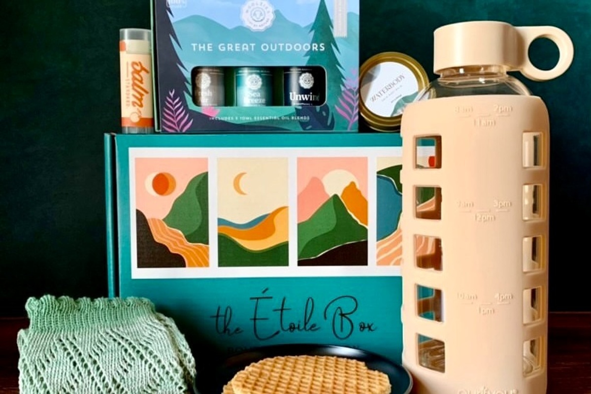 A closed Étoile subscription box surrounded by a water bottle, a stroopwaffel, candles and lip balm.