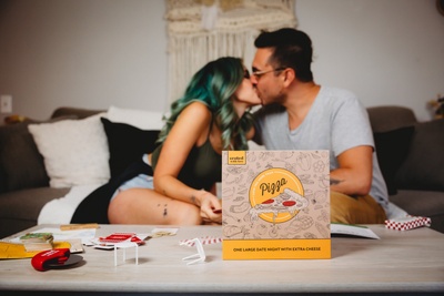 couple on couch kissing and enjoying a date night subscription box - pizza-themed games and activities