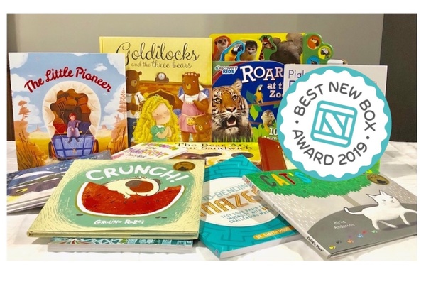 Several children's books on a table, some stacks, some standing up. With a best new box award.