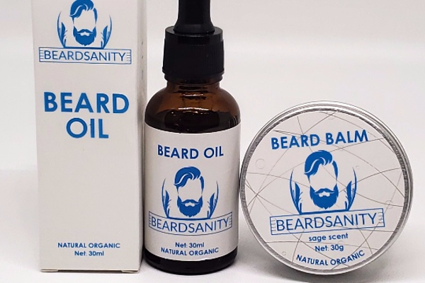 Items from a Beardsanity subscription box, including a tin of beard balm and a dropper bottle of beard oil.
