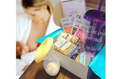 A the Boobie Box subscription box filled with a water bottle and snacks and food to help with milk supply.