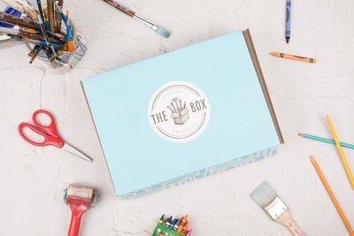 Outside the Box Creation's kids art box in its signature light blue color surrounded by art supplies on a flat surface