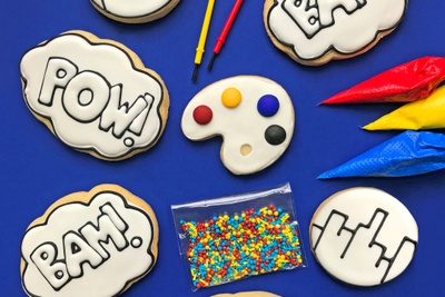 Several cookies, colored icing and paint brushes from a Color My Cookie subscription box.