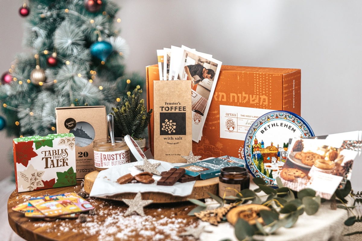 An Artza subscription box sitting on a table surrounded by candy and desserts, recipe cards and other times from Israel.