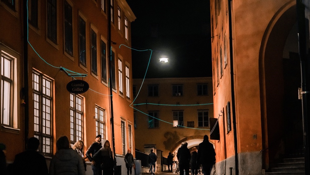 Människor i rörelse i centrala Uppsala under Allt ljus på Uppsala 2022. Kontverket heter Smalt ljus och är skapat av  Light Bureau.