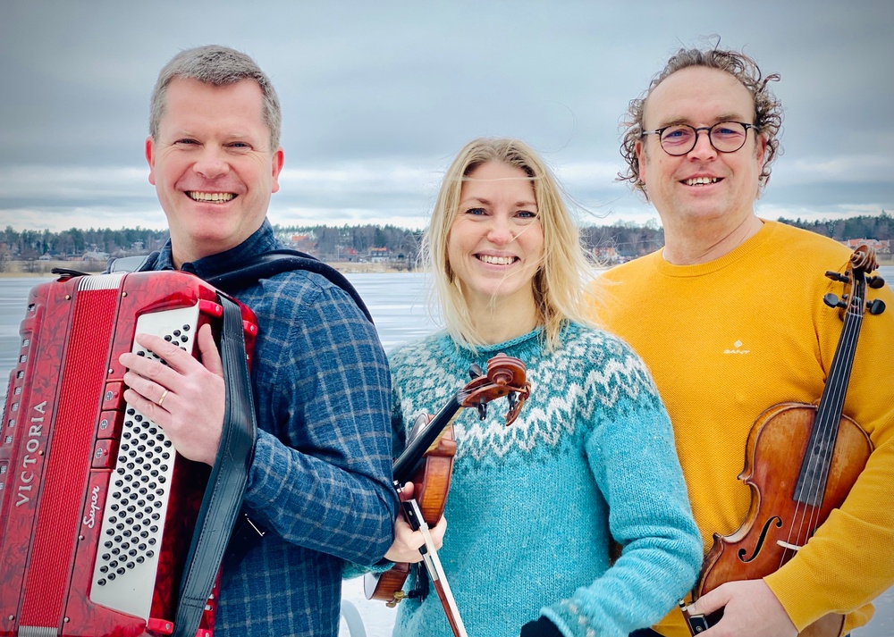 Bild på tre spelmän med instrument i vintrigt landskap.