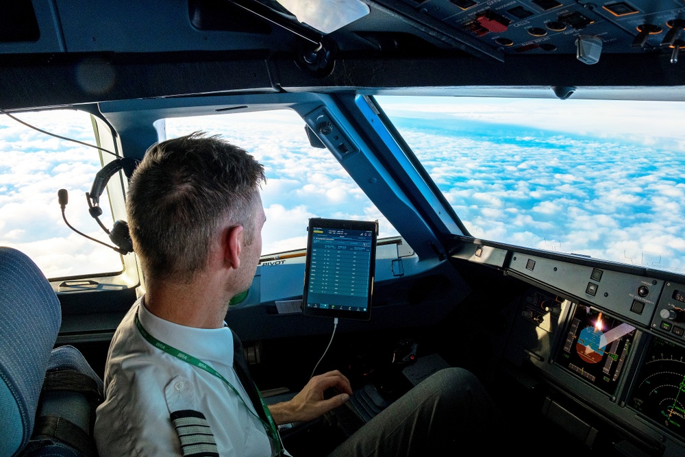En pilot från flygbolaget bra sitter i cockpit under flygning med vacker utsikt ovan molnen 