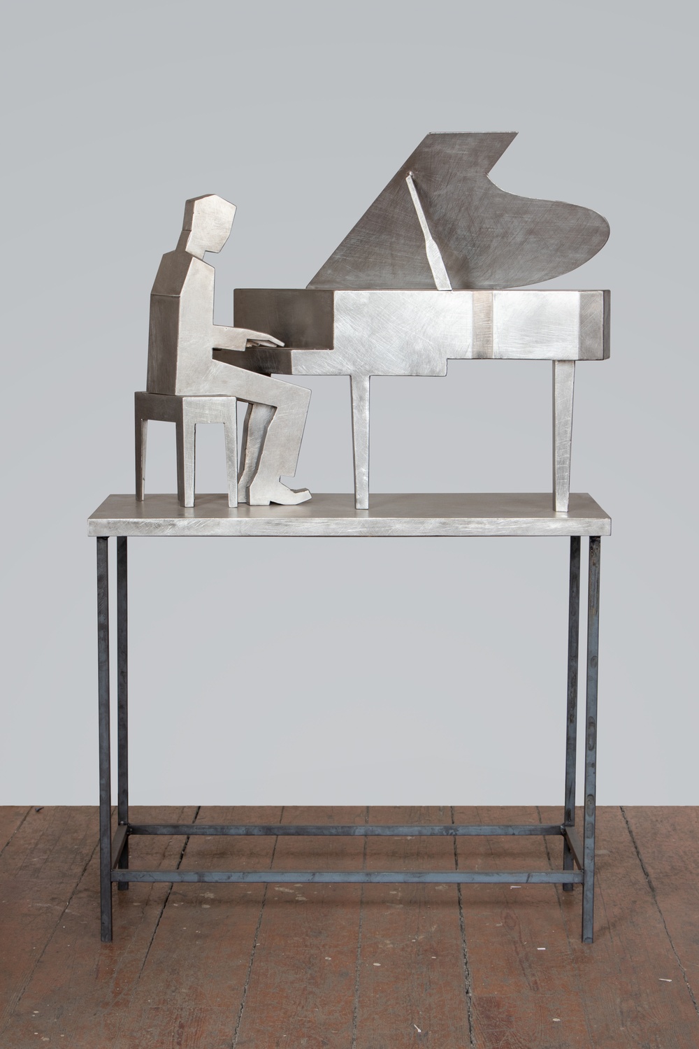 Skulptur  i rostfritt stål av pianist vid flygel.